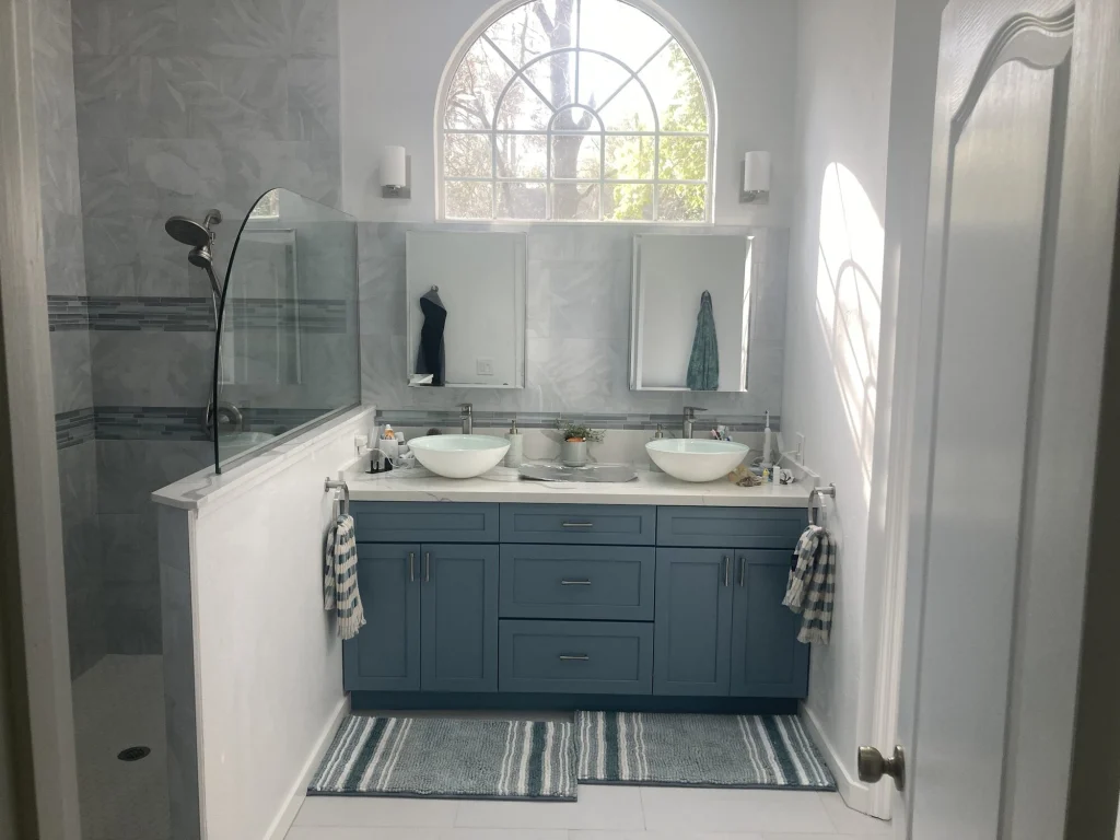 A double vanity with blue cabinets, vessel sinks and an arched window