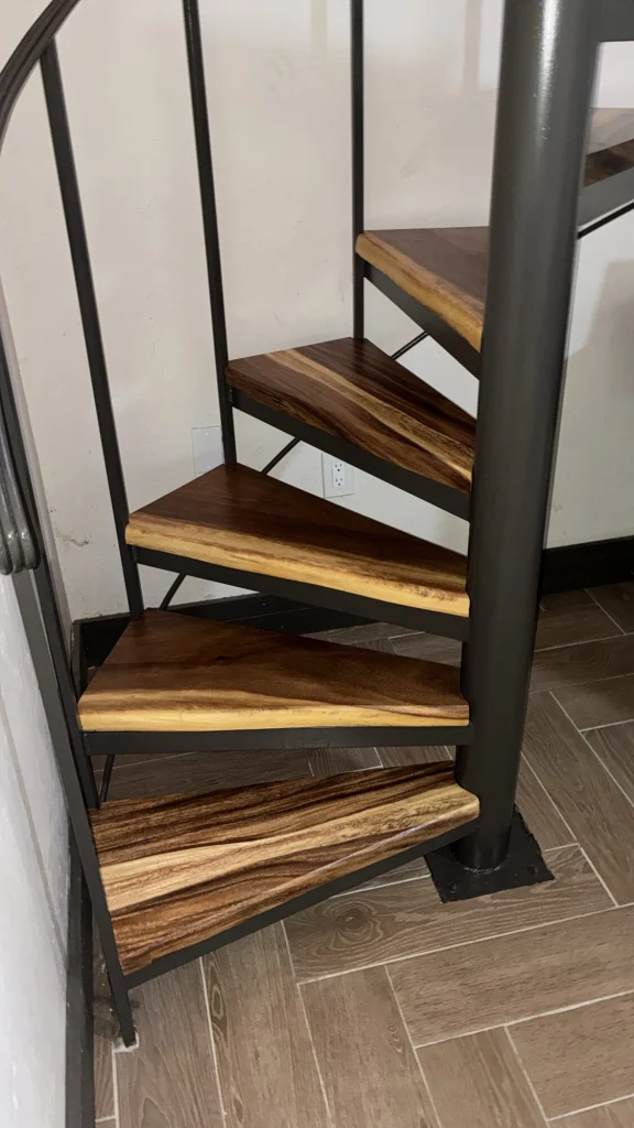 A spiral staircase with live-edge wood treads on a dark steel frame