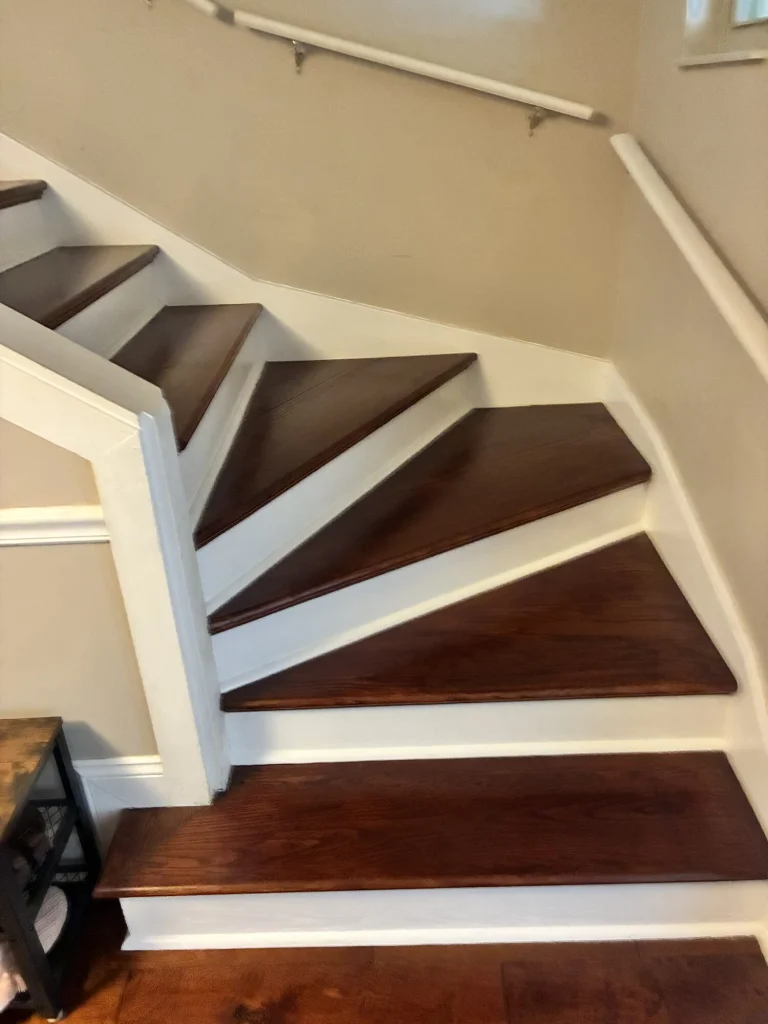 A winding staircase with dark stained wood treads and white risers